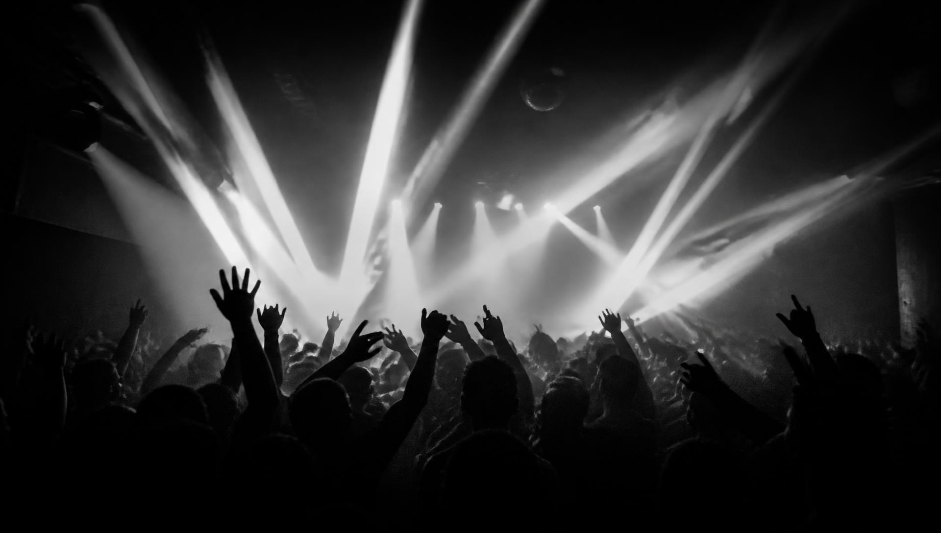 Crowd with hands raised under stage lights at a DJ Ironviti event